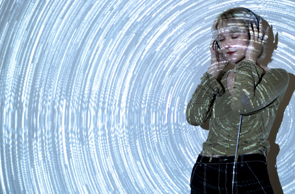 Personne Ă©coutant de la musique avec un casque, plongĂ©e dans un tourbillon lumineux abstrait, symbolisant lâinspiration sonore et numĂ©rique.