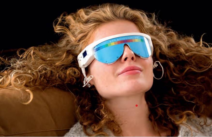 Femme détendue portant les lunettes de luminothérapie et de relaxation PSiO, allongée confortablement, yeux fermés, profitant d'une séance de bien-être mental.