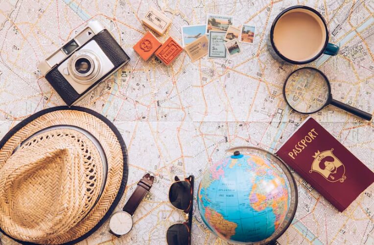 Photo d'une carte avec des objets de voyage : appareil photo, passeport, globe terrestre, loupe, chapeau, etc.